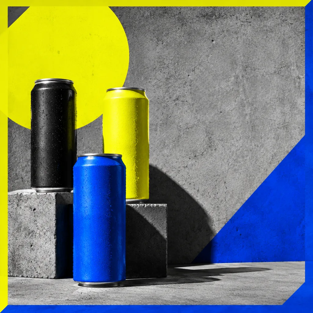 Three unbranded drink cans in black, yellow and blue on raw concrete, bold poster